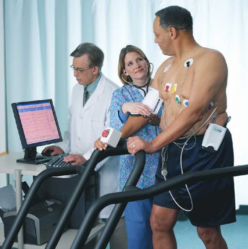 A patient undergoing a thread mill stress test with medical professionals to monitor and assist him.